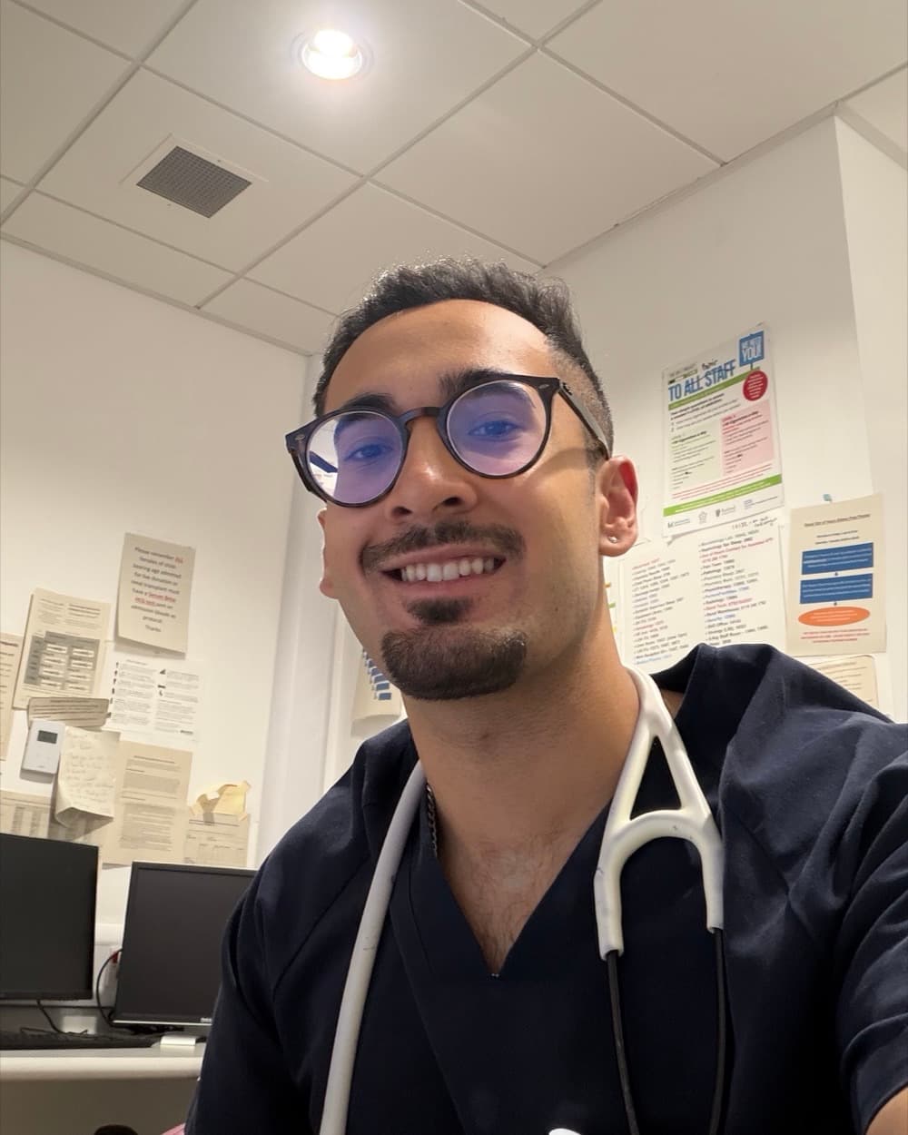 Dr Dev Gakhar in scrubs, with a stethoscope, in a hospital office